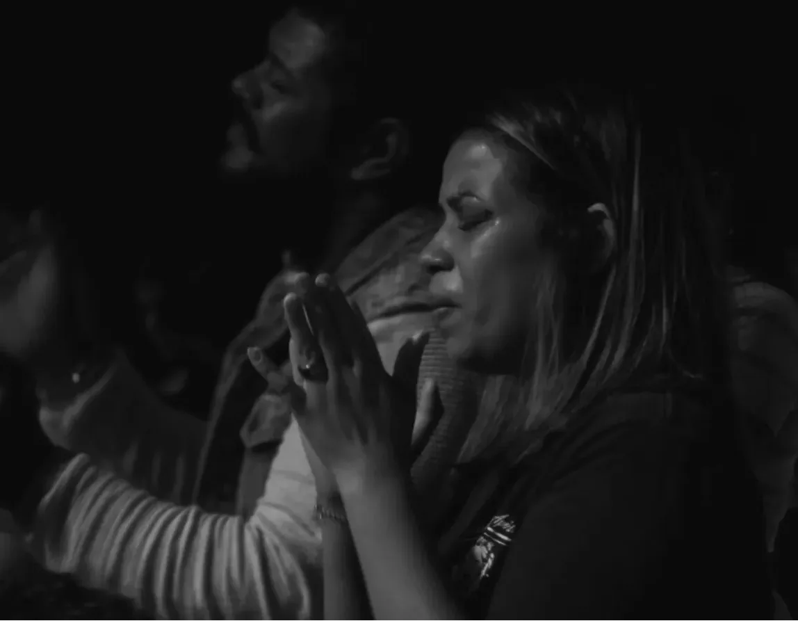 Uma mulher de mãos juntas, em oração.