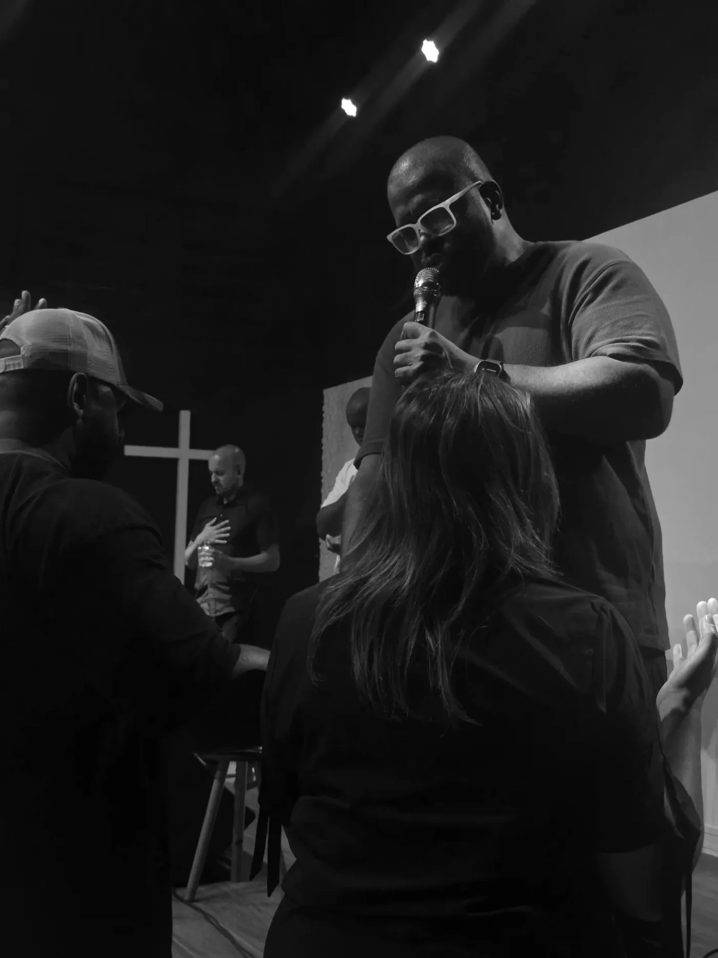 Pregador ministrando sobre uma mulher, com a mão sobre a cabeça dela.